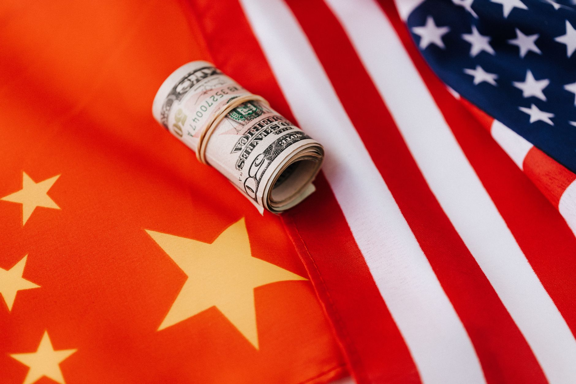 From above of roll of dollar bills tied with rubber band on bright American flag with stars and stripes symbolizing unity and peace