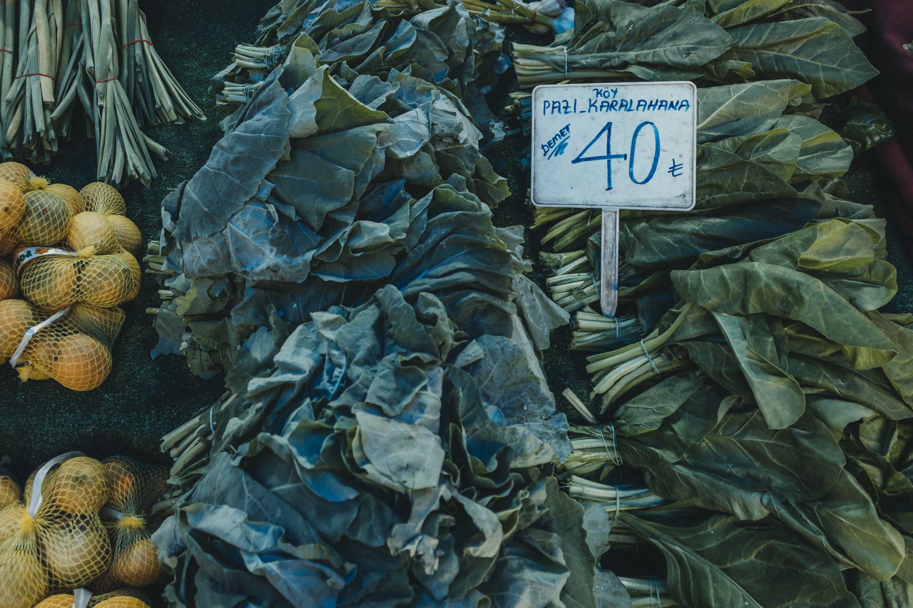 Vibrant market display with collard greens and oranges, price listed as 40 TL.