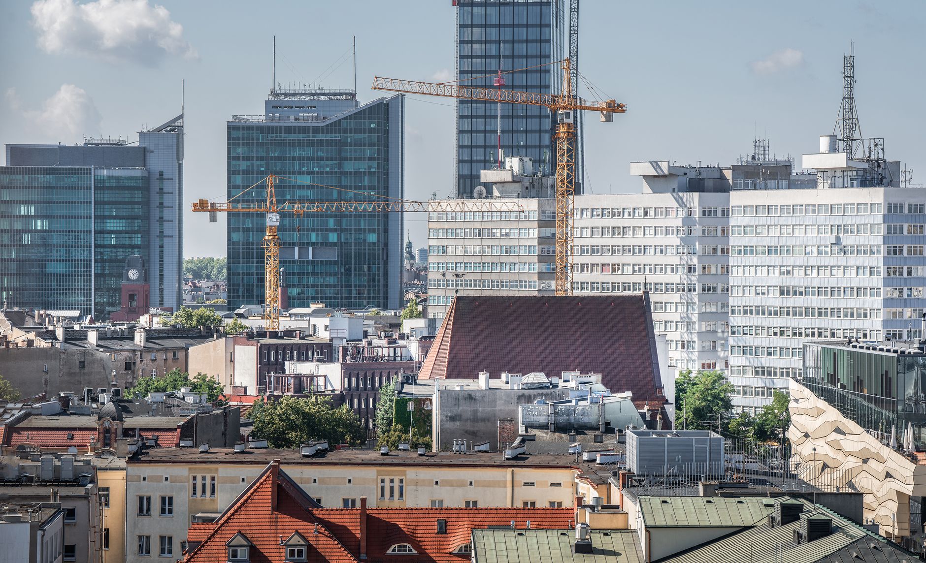 Urban skyline of Poznań with cranes and modern architecture in view.
