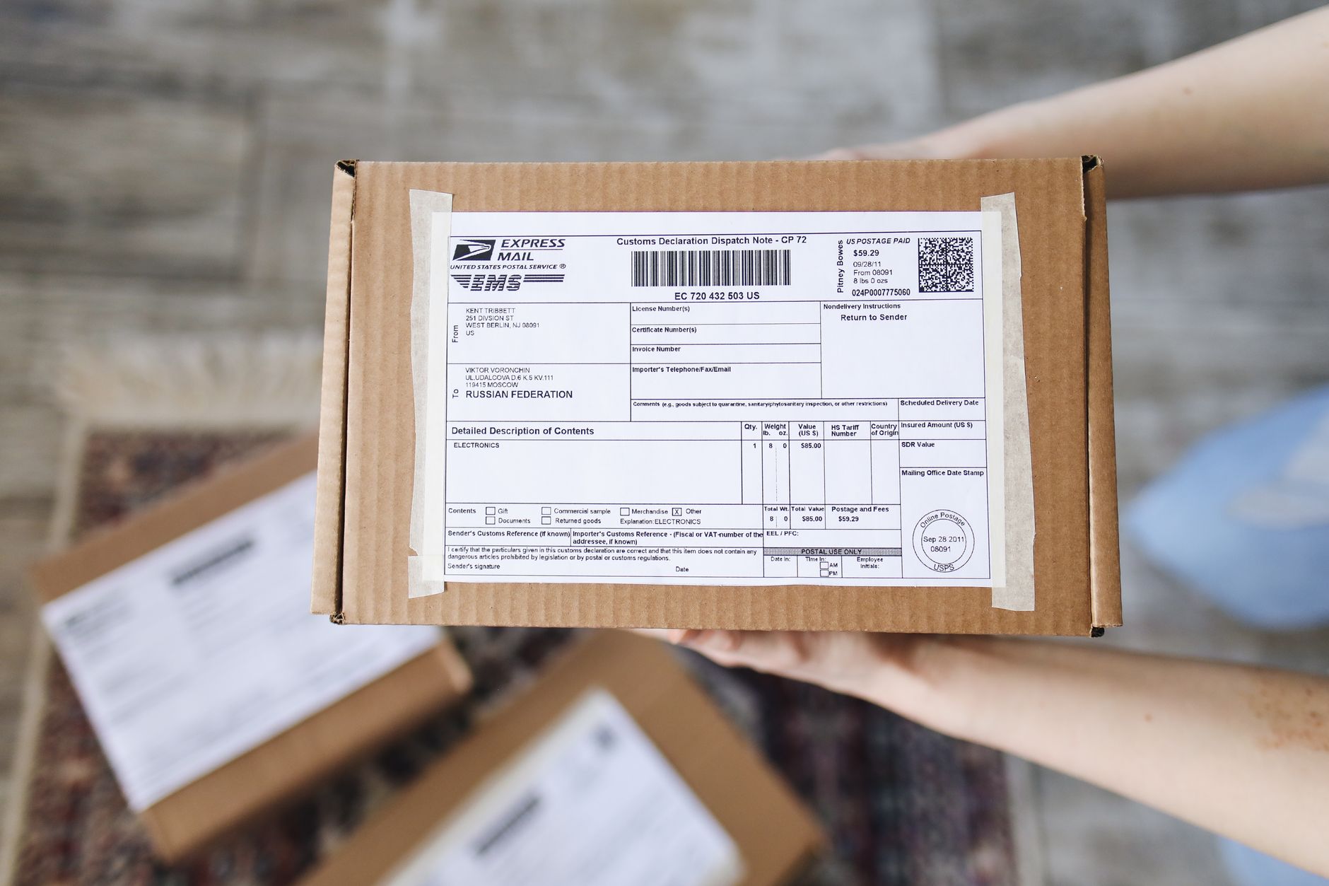 Top view of hands holding an express mail parcel with a customs declaration.