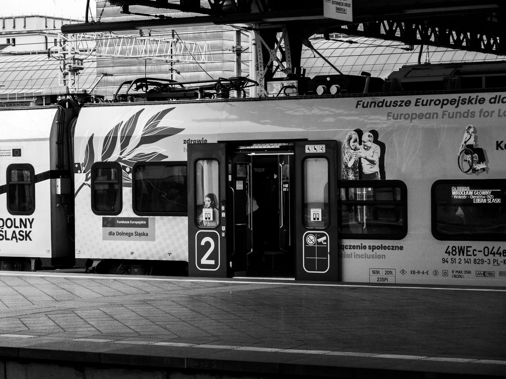 Black and white image of a train at a station with passengers visible inside, providing a classic urban feel.