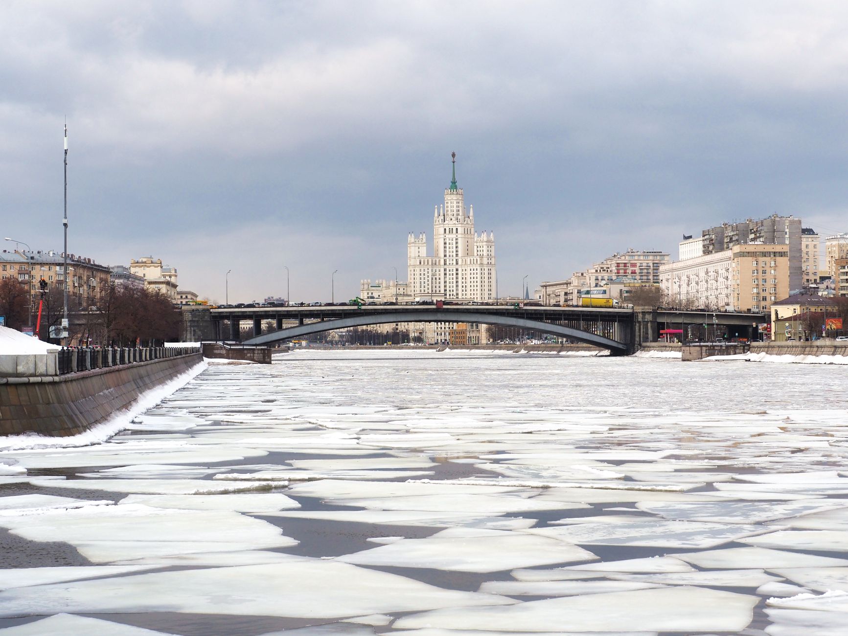 A winter view of the frozen Moskva River with the iconic Kotelnicheskaya Building in Moscow, Russia.
