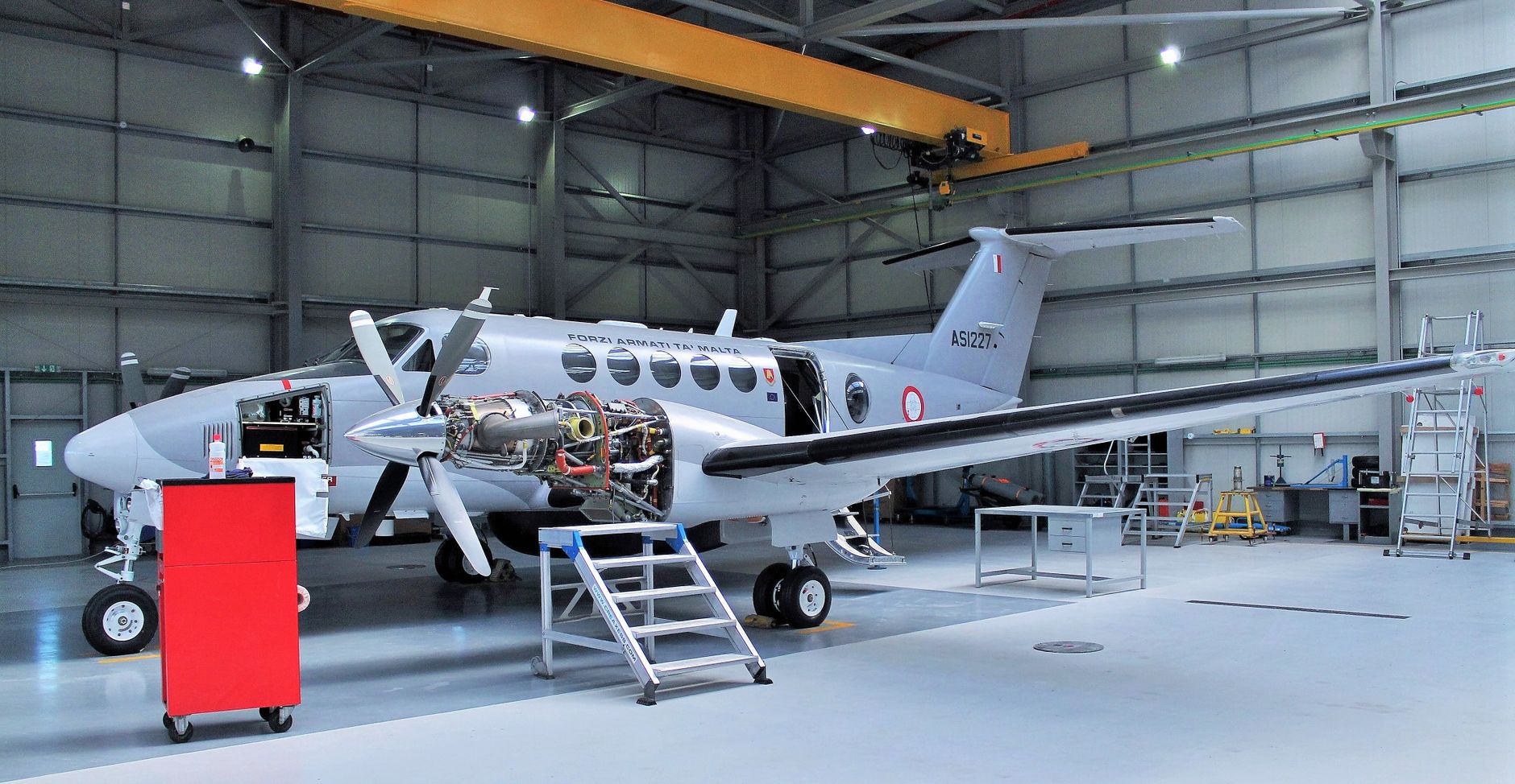 Aircraft undergoing maintenance in a spacious modern hangar.