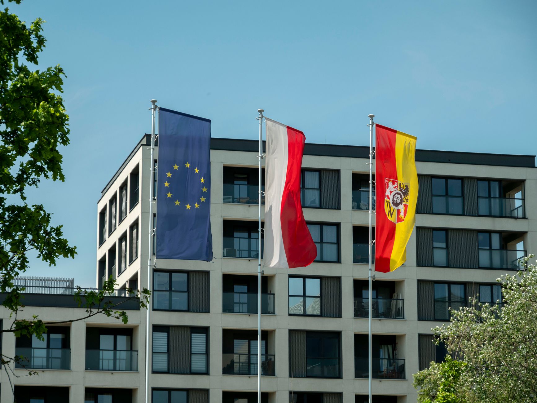 Flags of the European Union, Poland, and Wrocław against modern architecture in Wrocław, Poland.