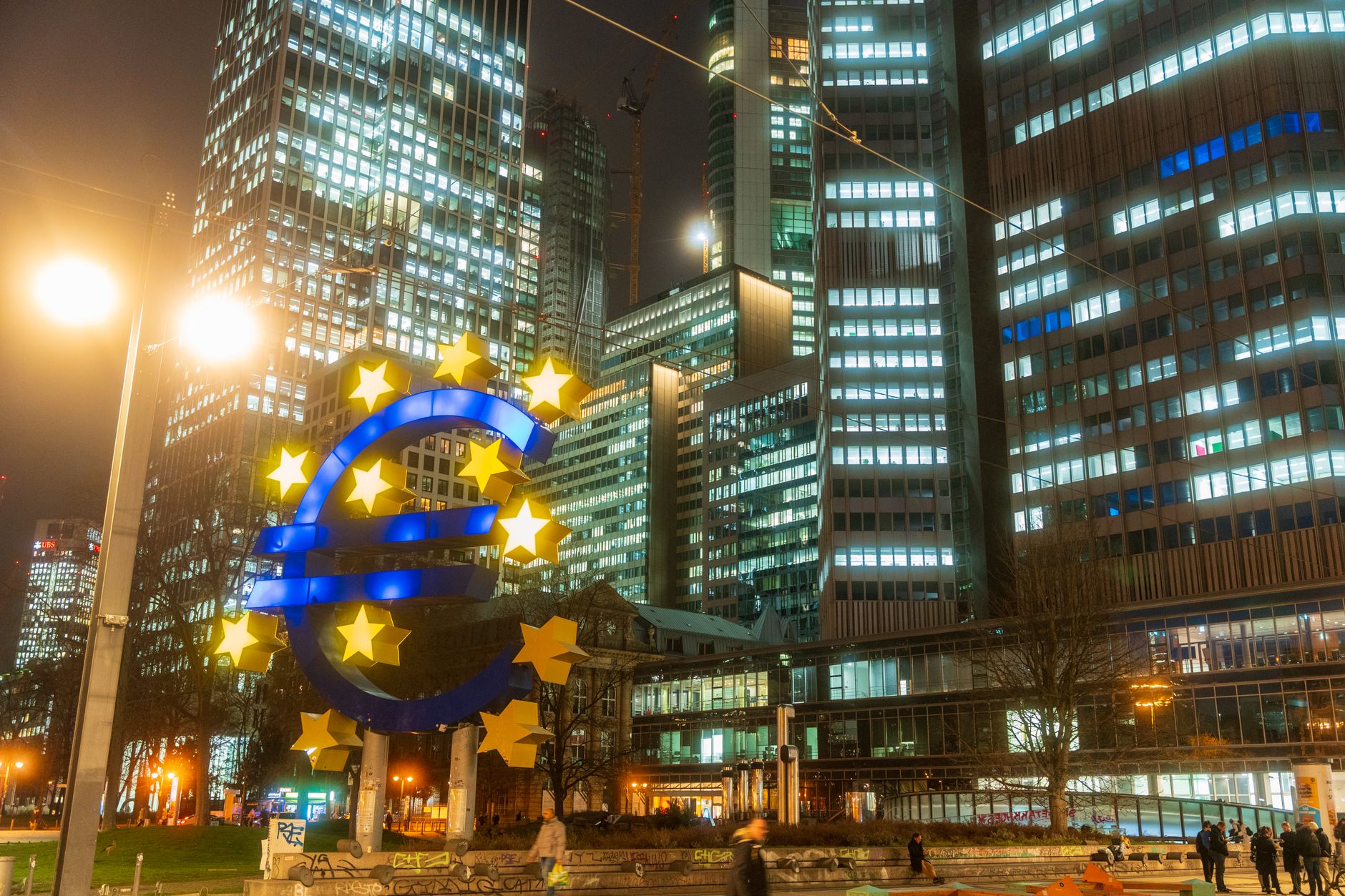 Night view of the iconic Euro sculpture in Frankfurt's bustling financial district.