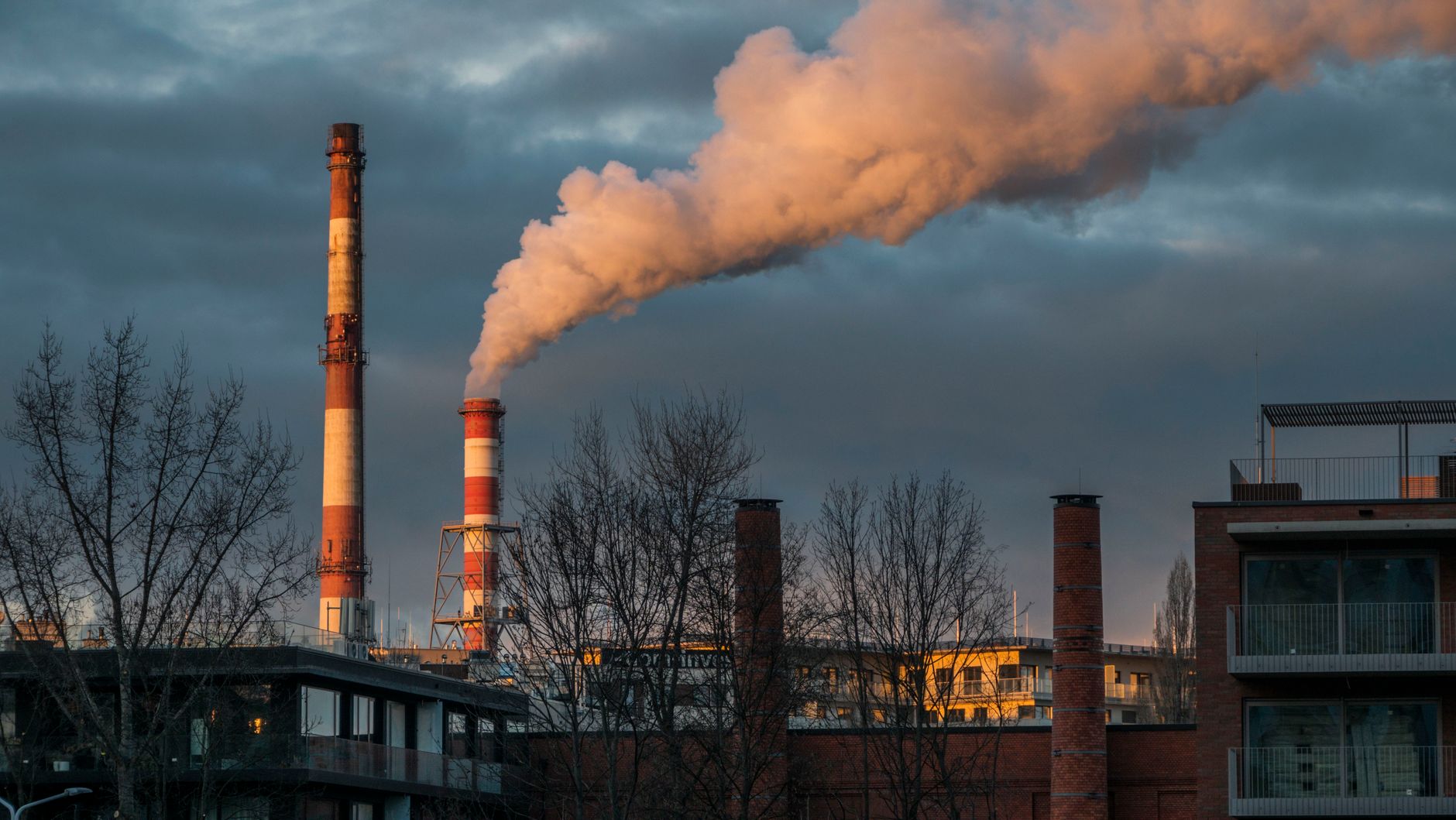 Chimneys of an industrial plant releasing smoke against a dramatic sky in Wrocław.