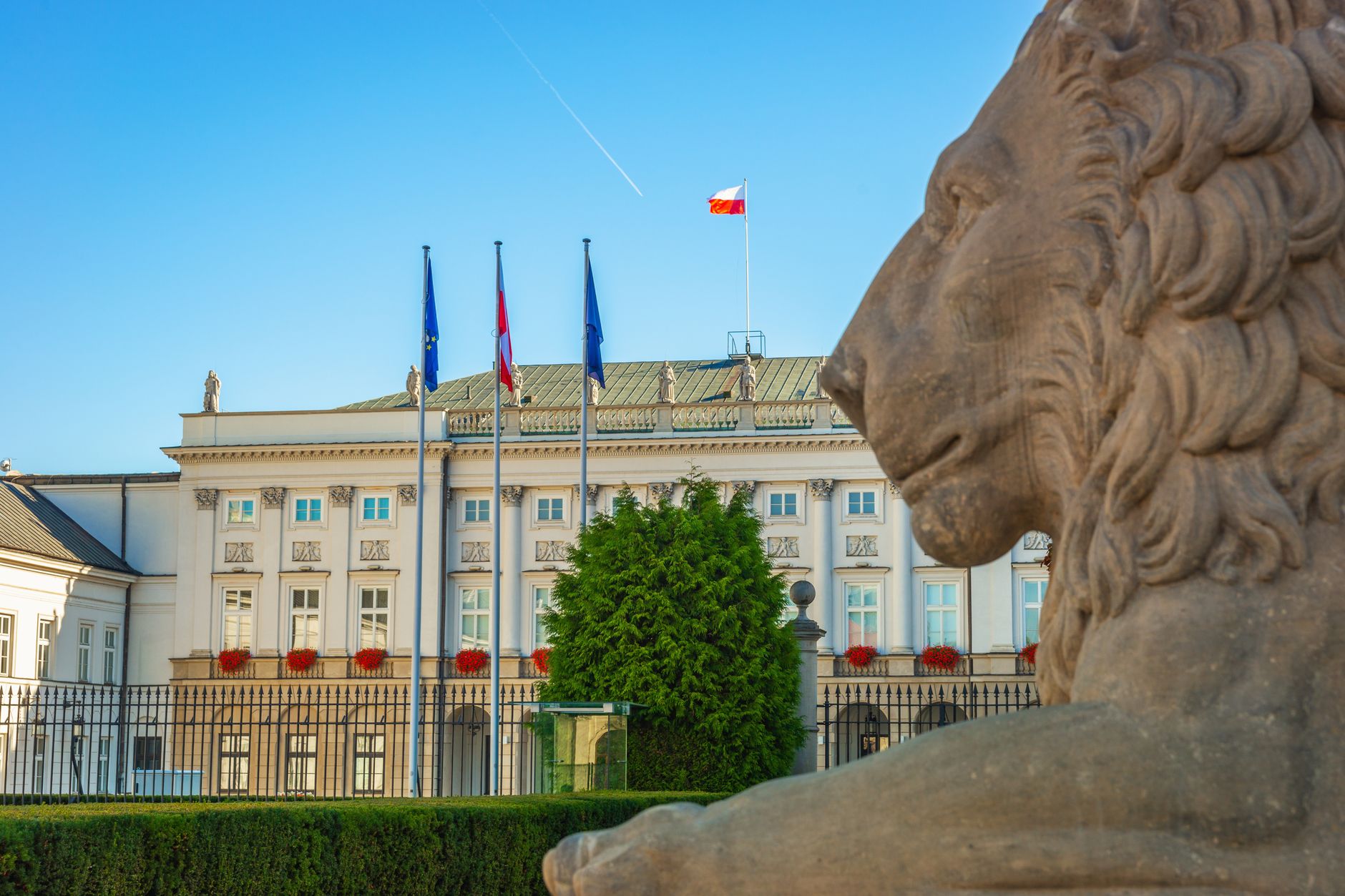 Elegant view of Presidential Palace in Warsaw with a prominent stone lion statue.
