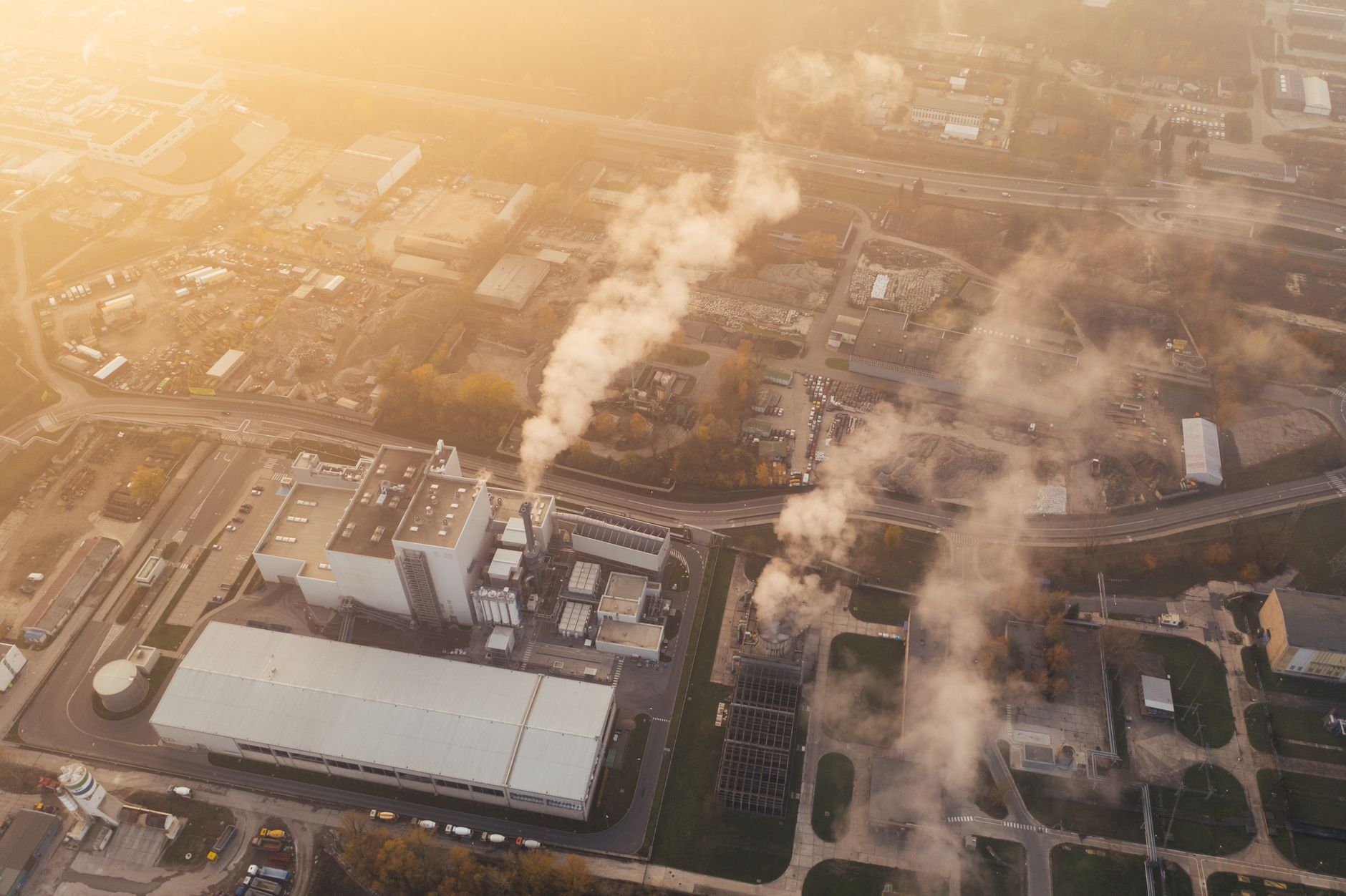 An aerial shot capturing a factory complex with visible smoke in Poznań, Poland.