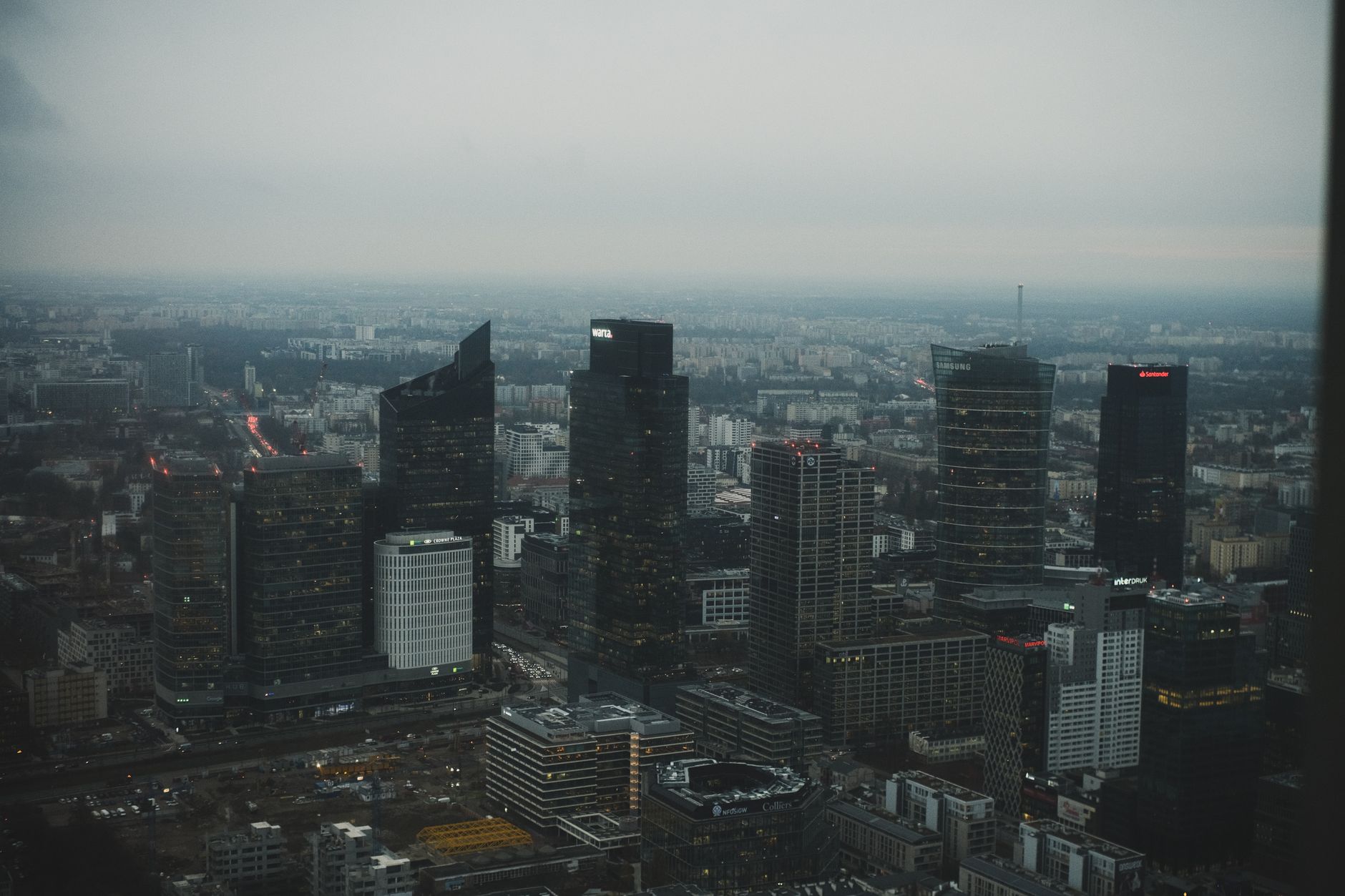 Stunning aerial view of Warsaw's modern skyline against a cloudy dusk sky.