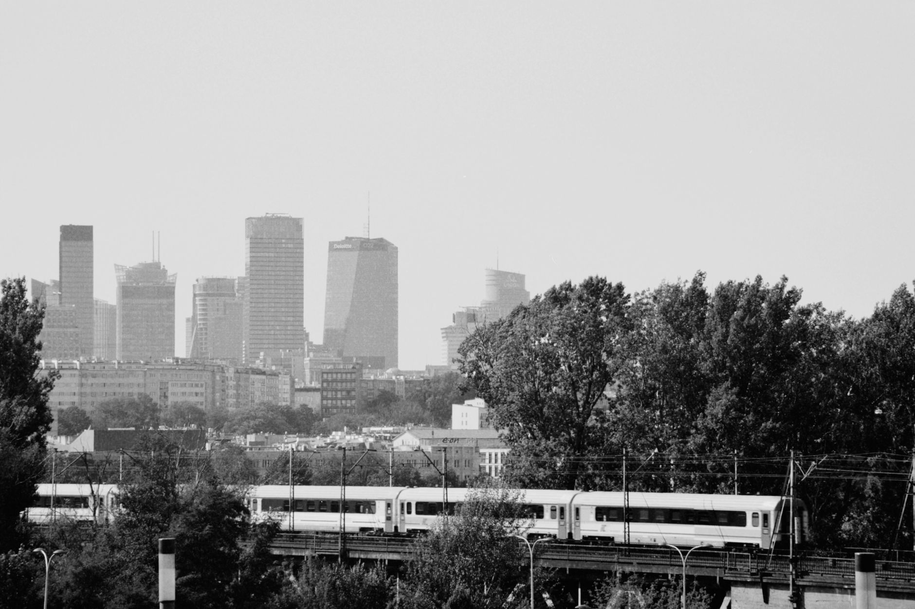 Black and white view of Warsaw's modern skyline with a train traveling below.