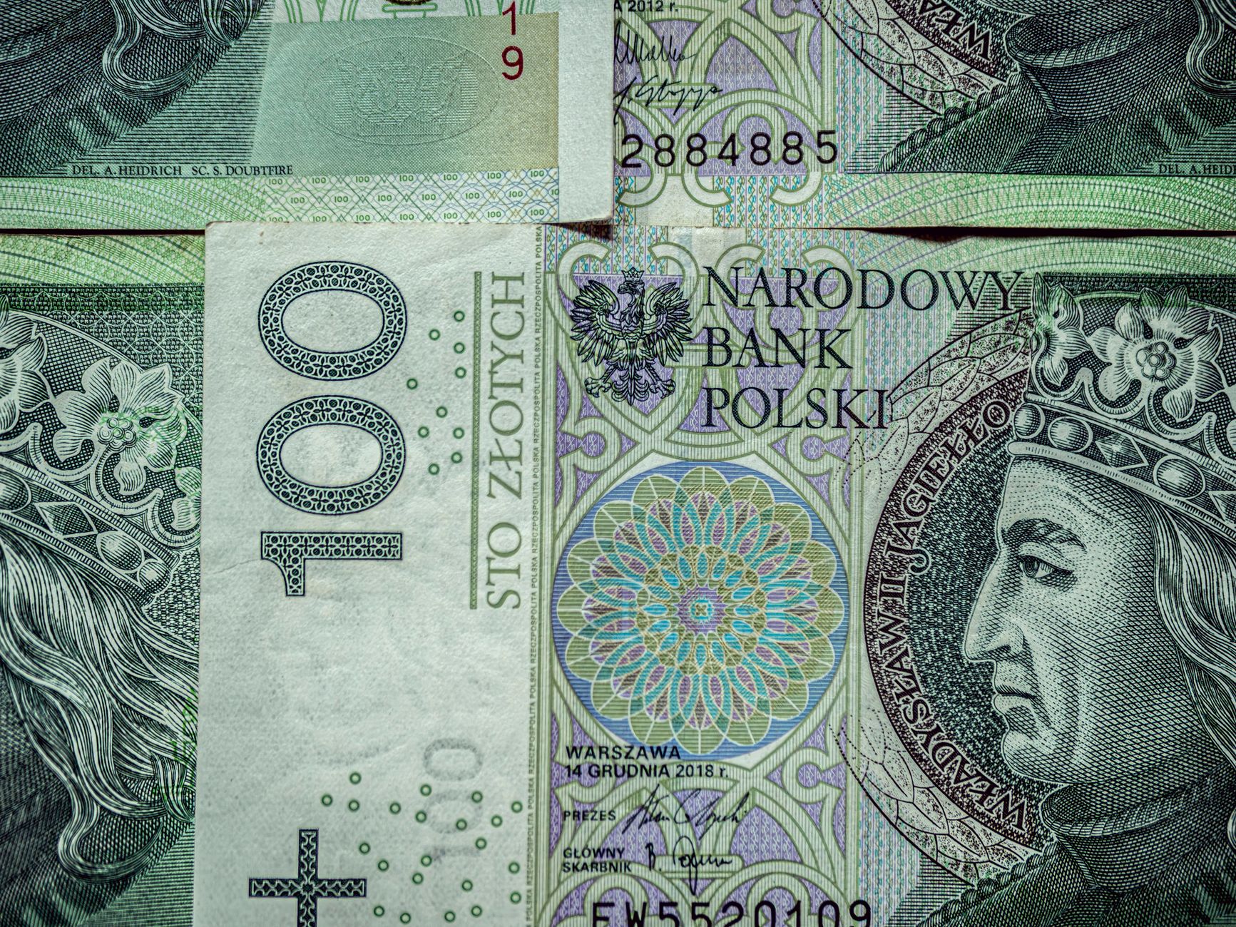 Close-up of 100 Polish Zloty banknotes with intricate designs and text.