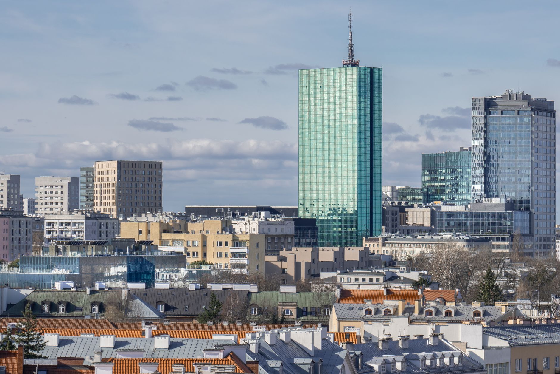 A sunny daytime cityscape of Warsaw's modern skyline with high-rise buildings and distinctive architecture.