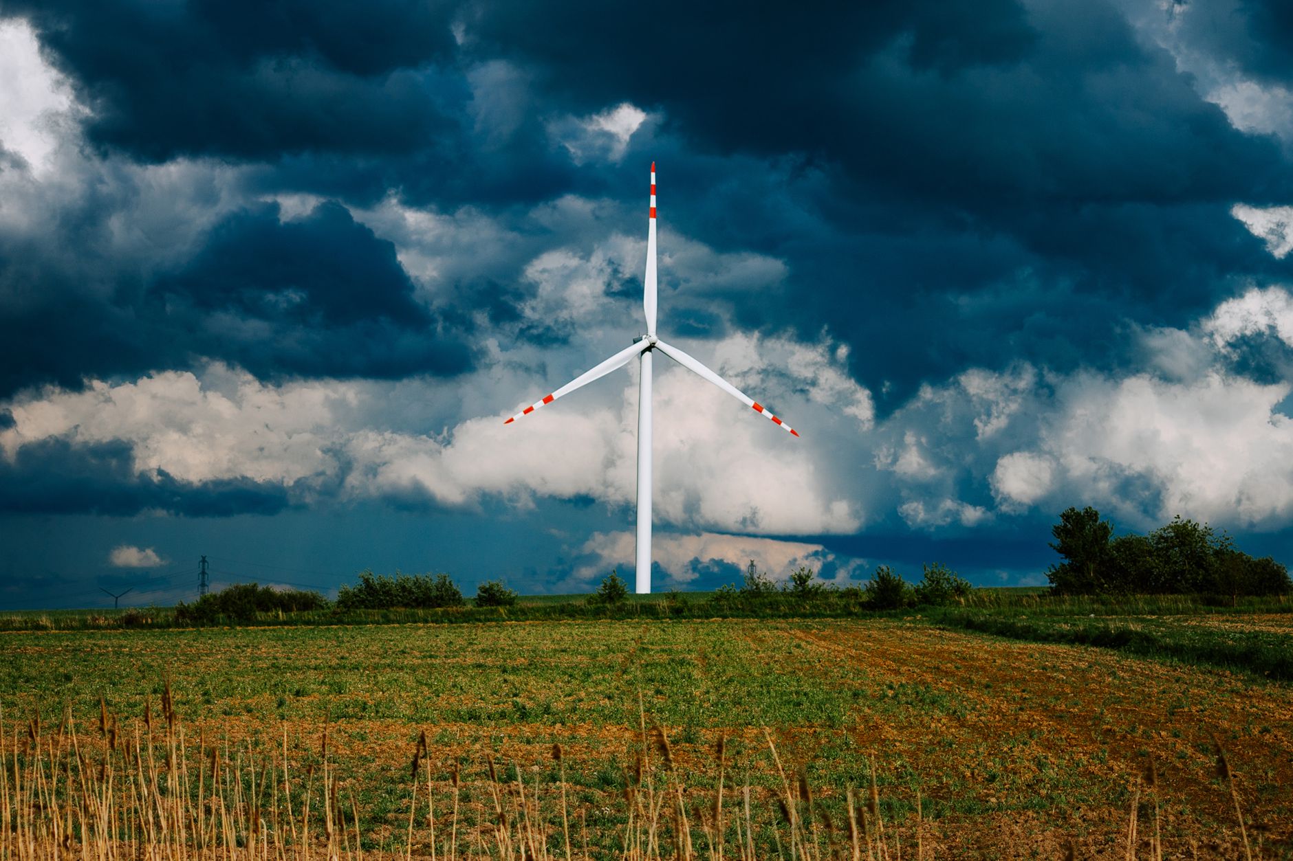 A wind turbine stands majestically in Konin, Poland, beneath a dramatic cloudy sky.