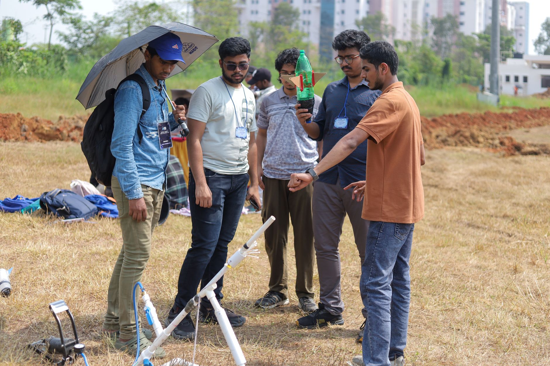 Group of students in Kharagpur conducting an outdoor rocket launch experiment on a sunny day.
