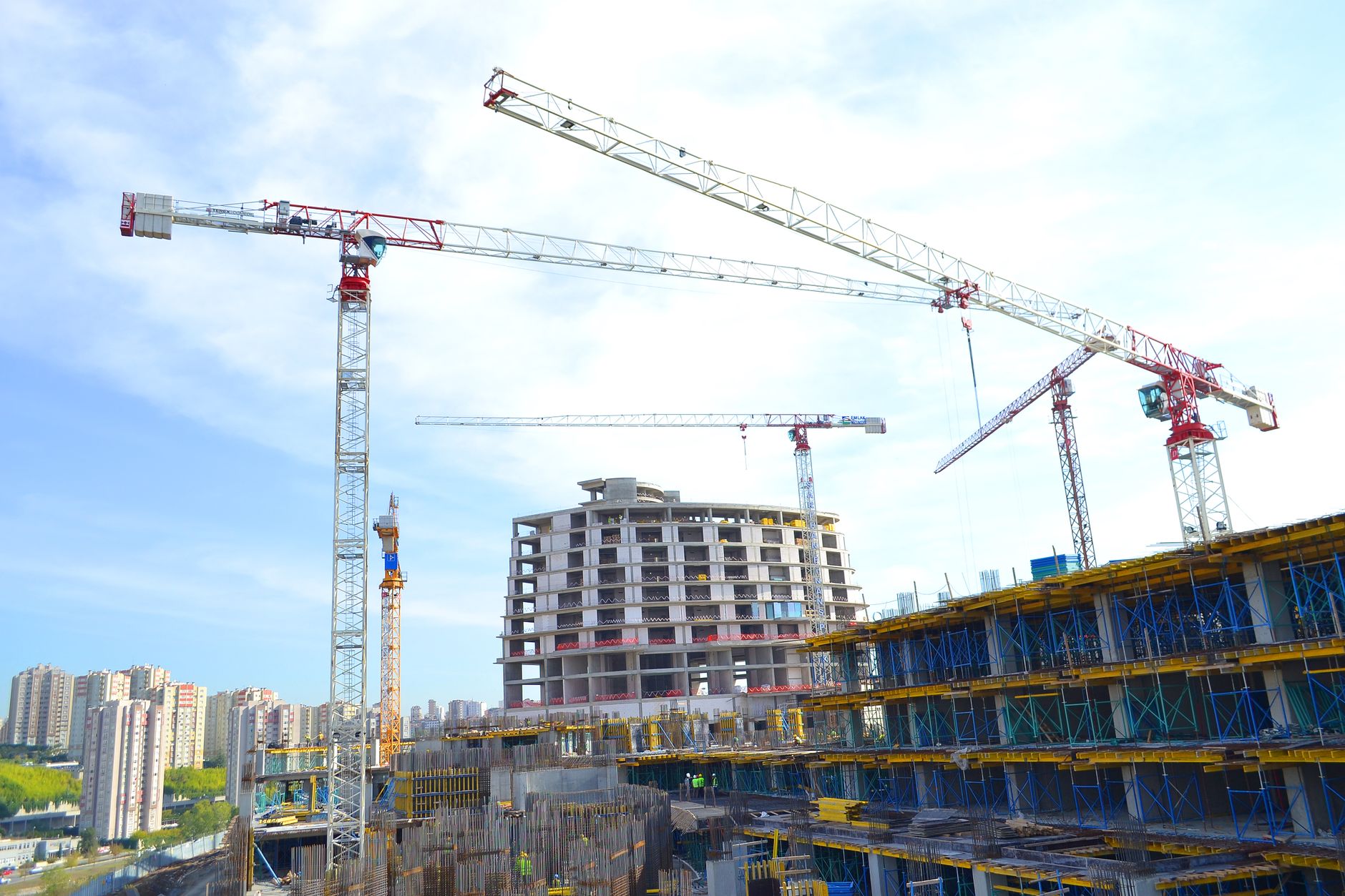 Urban construction site featuring multiple tower cranes against a city skyline.